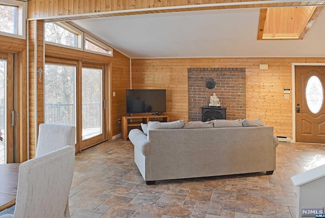 living room with a wood stove, vaulted ceiling, a baseboard heating unit, and wood walls