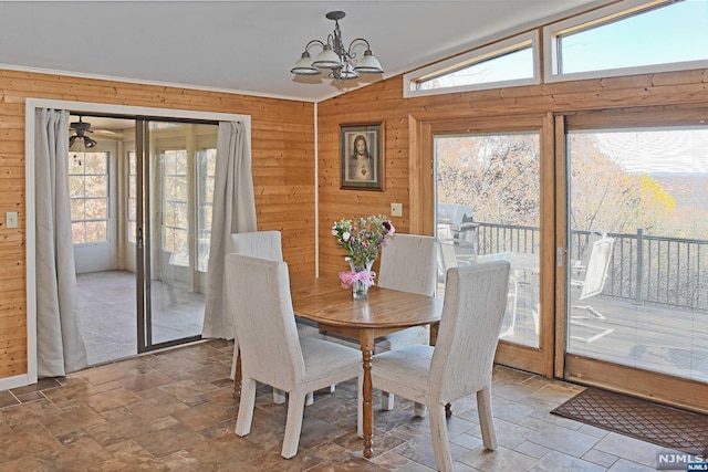 dining room featuring vaulted ceiling, a wealth of natural light, a notable chandelier, and wood walls