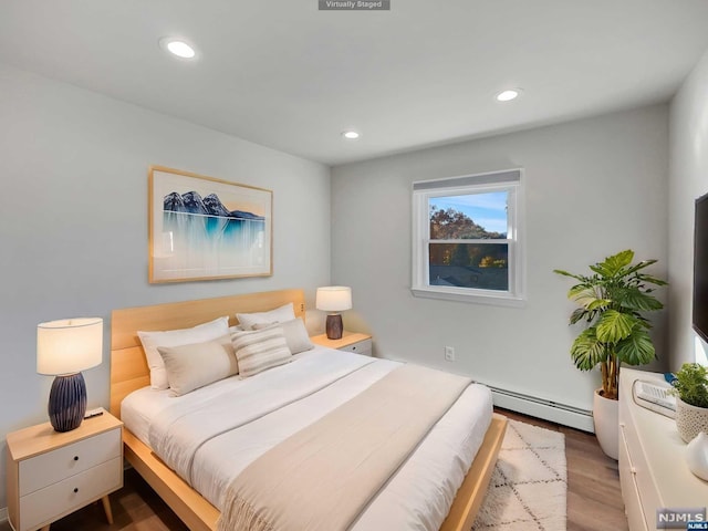 bedroom featuring baseboard heating and hardwood / wood-style floors