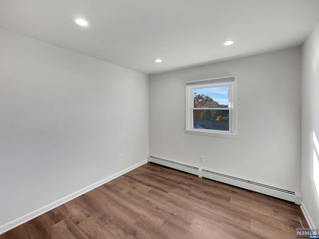 spare room featuring wood-type flooring and a baseboard radiator