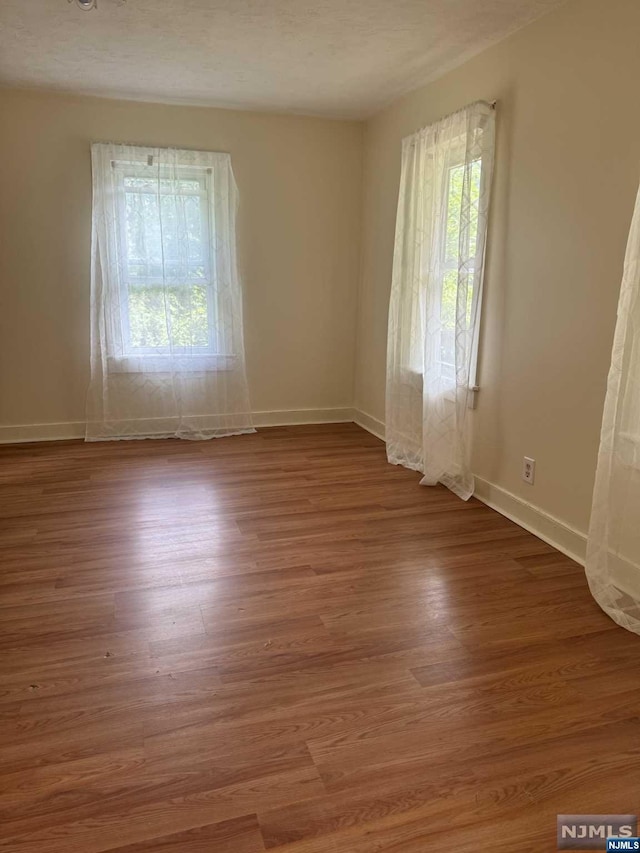 empty room with wood-type flooring and a textured ceiling