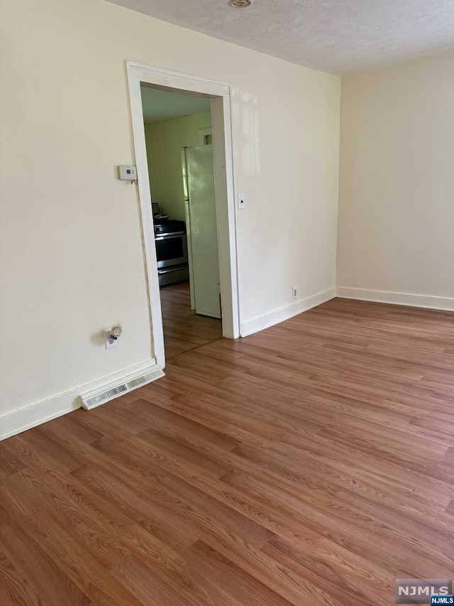 empty room featuring wood-type flooring and a textured ceiling