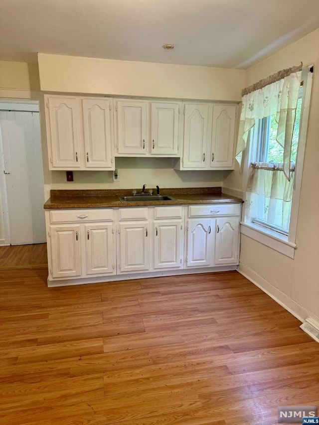 kitchen featuring light hardwood / wood-style floors, white cabinetry, and sink