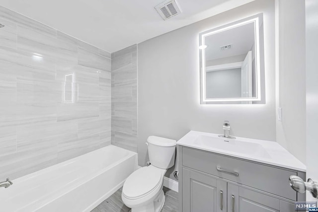 full bathroom featuring hardwood / wood-style flooring, vanity, toilet, and tiled shower / bath