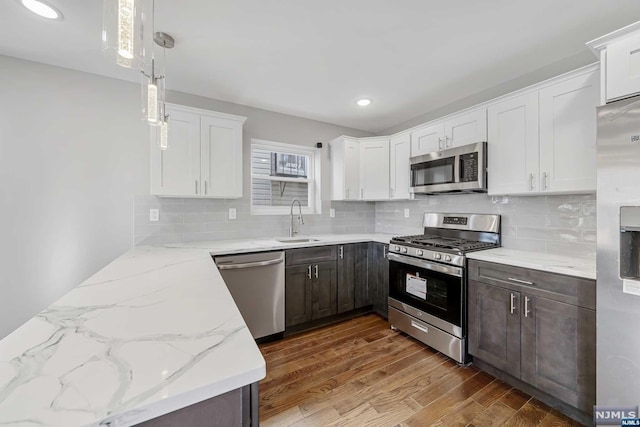 kitchen with white cabinets, decorative light fixtures, stainless steel appliances, and sink