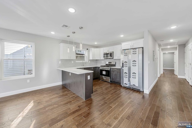 kitchen featuring appliances with stainless steel finishes, dark wood-type flooring, white cabinetry, and pendant lighting