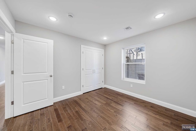 unfurnished bedroom with a closet and dark hardwood / wood-style floors