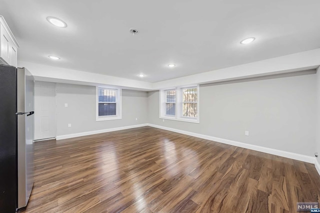 basement with stainless steel fridge and dark hardwood / wood-style flooring