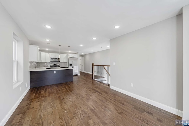 kitchen featuring white cabinetry, dark hardwood / wood-style flooring, backsplash, pendant lighting, and appliances with stainless steel finishes