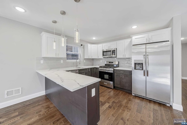 kitchen with white cabinets, pendant lighting, dark hardwood / wood-style flooring, and stainless steel appliances