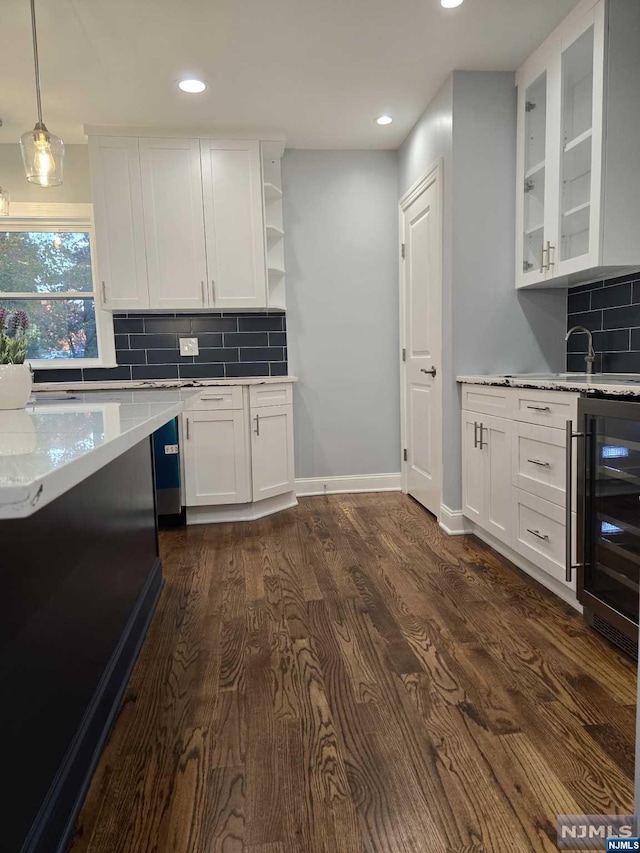 kitchen featuring dark wood-type flooring, wine cooler, backsplash, decorative light fixtures, and white cabinets