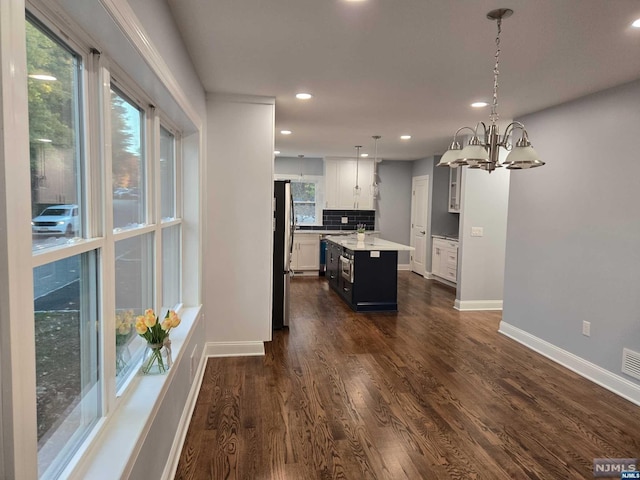 kitchen featuring dark wood-type flooring, hanging light fixtures, a kitchen island, white cabinetry, and a chandelier