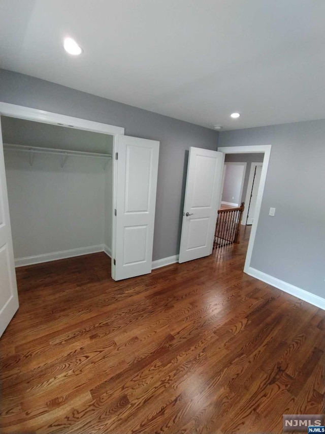 unfurnished bedroom with a closet and dark hardwood / wood-style floors