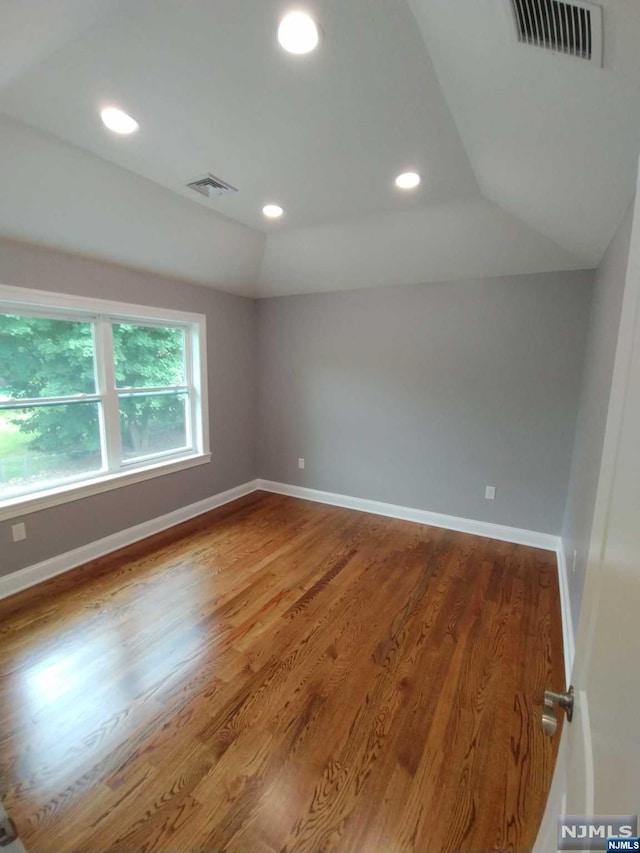 spare room featuring hardwood / wood-style flooring and lofted ceiling