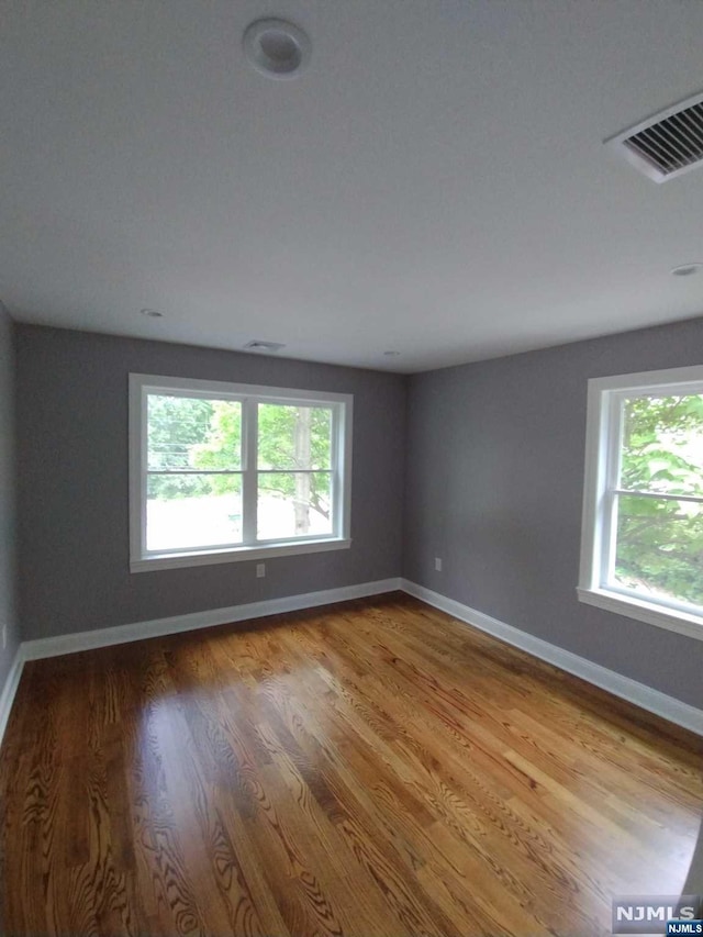 unfurnished room featuring plenty of natural light and hardwood / wood-style flooring