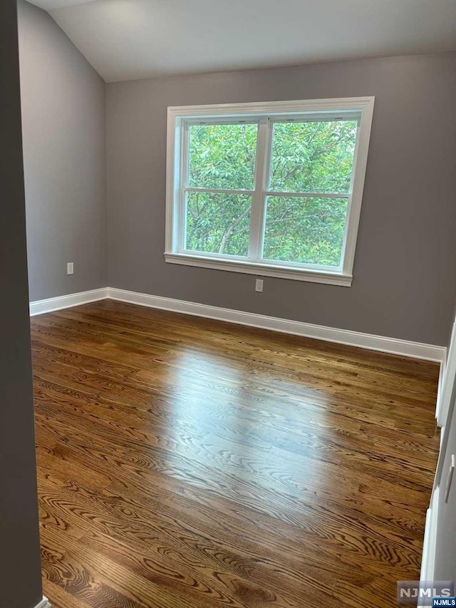 spare room with hardwood / wood-style flooring and vaulted ceiling