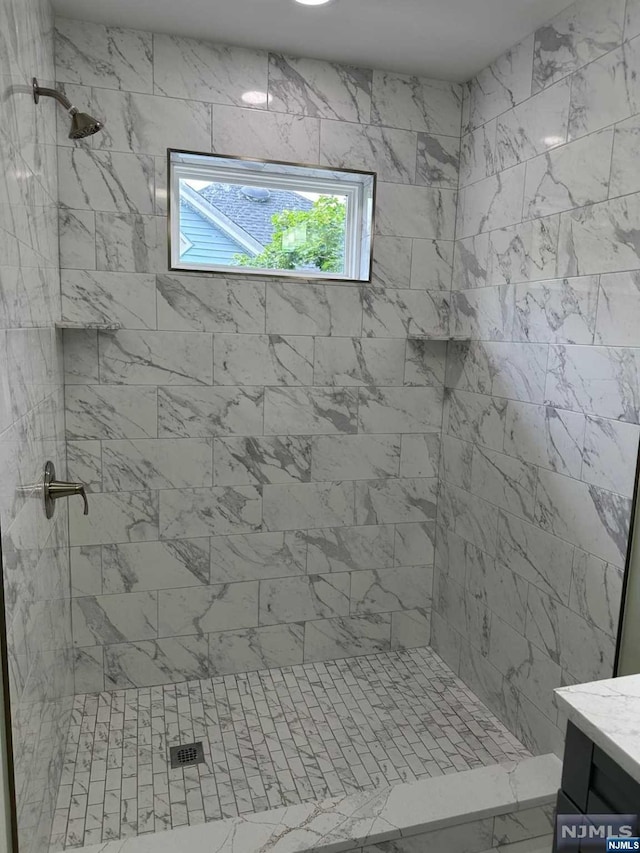 bathroom featuring tiled shower and vanity