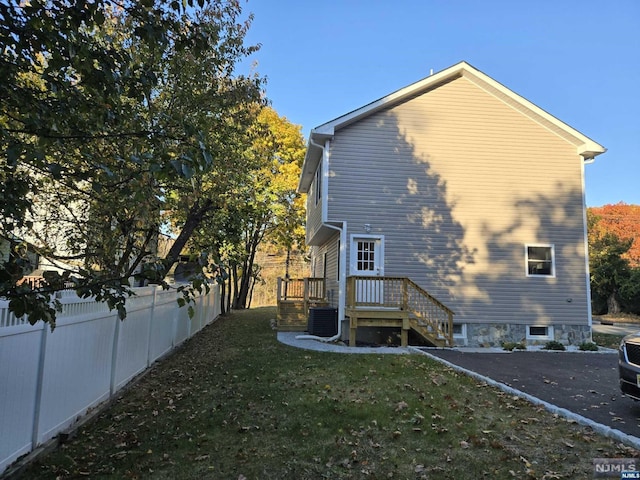 back of house featuring central air condition unit and a yard