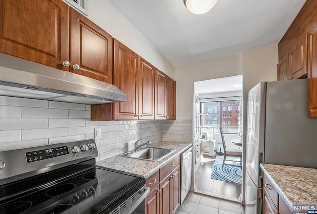 kitchen featuring appliances with stainless steel finishes, light wood-type flooring, tasteful backsplash, light stone counters, and sink