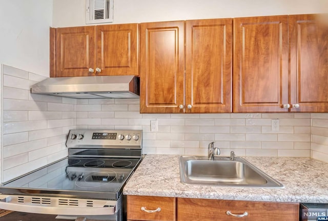 kitchen featuring decorative backsplash, electric range, sink, and light stone counters