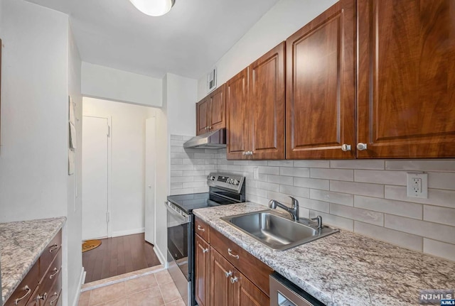 kitchen with light stone countertops, backsplash, sink, light tile patterned floors, and stainless steel electric range