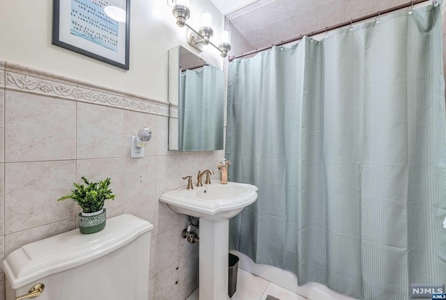 bathroom featuring sink, a shower with curtain, tile patterned floors, toilet, and tile walls