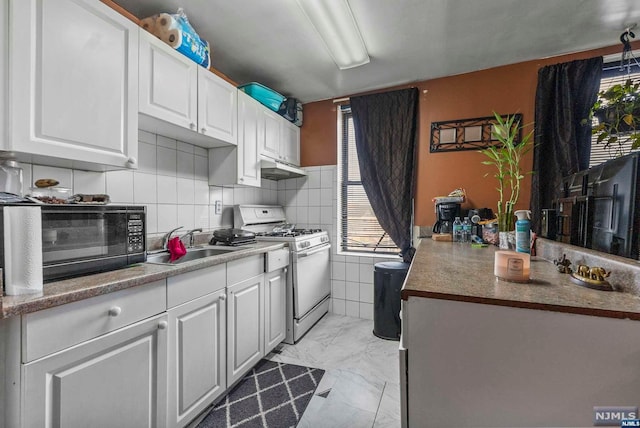 kitchen featuring white cabinets, white gas stove, backsplash, and sink