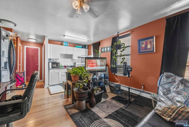 interior space featuring light wood-type flooring, a baseboard radiator, and ceiling fan