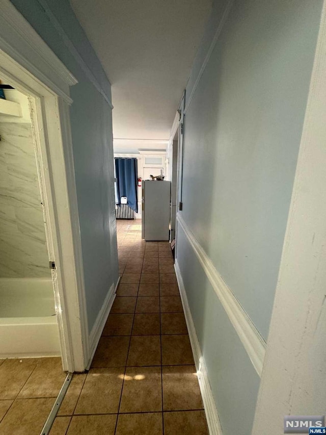 hallway featuring dark tile patterned flooring and ornamental molding