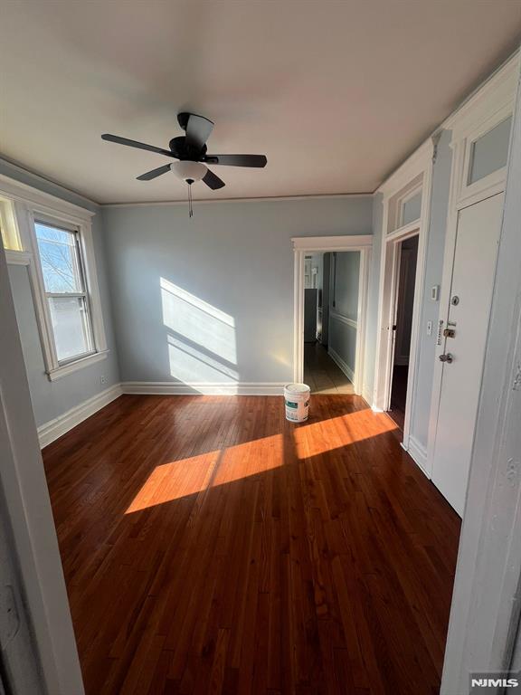 empty room with dark hardwood / wood-style floors and ceiling fan