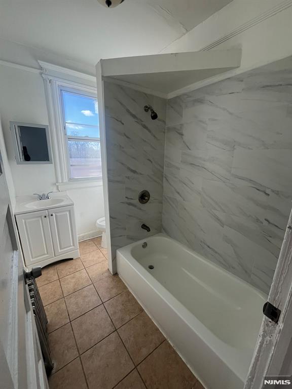 full bathroom featuring toilet, tile patterned floors, vanity, and tiled shower / bath