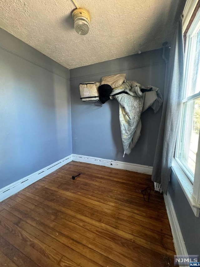 unfurnished room featuring a textured ceiling and dark hardwood / wood-style floors