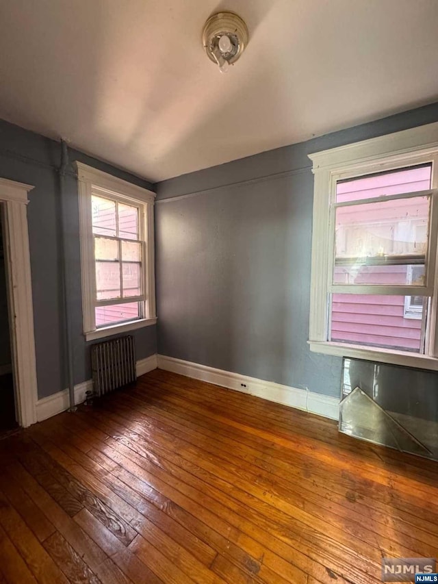 empty room featuring hardwood / wood-style flooring and radiator