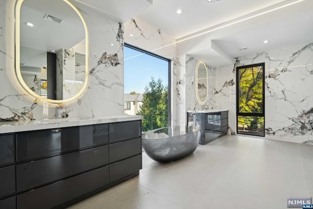 bathroom featuring a bathing tub, vanity, concrete flooring, and a wealth of natural light