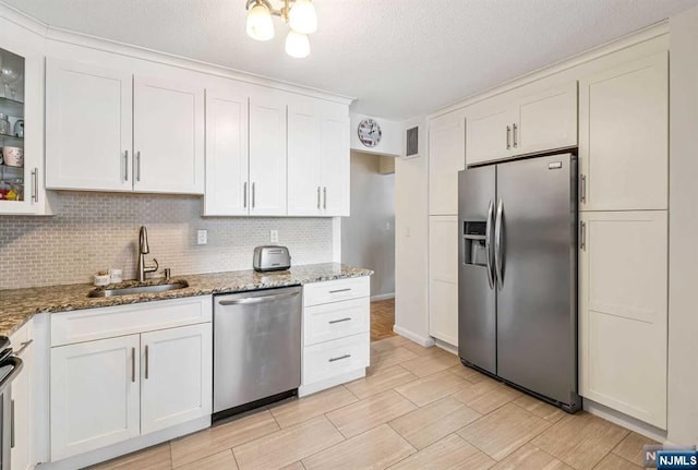 kitchen featuring light stone counters, stainless steel appliances, tasteful backsplash, white cabinets, and sink