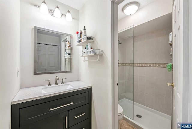 bathroom with a tile shower, vanity, and toilet