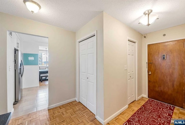 foyer entrance with a textured ceiling and light parquet floors