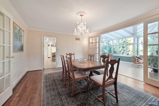 dining space featuring french doors, dark hardwood / wood-style flooring, a notable chandelier, and ornamental molding