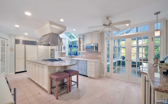 kitchen with white cabinetry, french doors, tasteful backsplash, a kitchen island, and appliances with stainless steel finishes