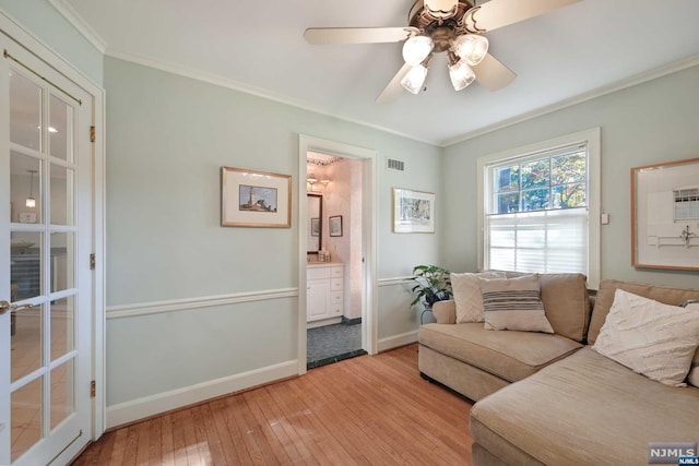 living room with light hardwood / wood-style floors, ceiling fan, and ornamental molding