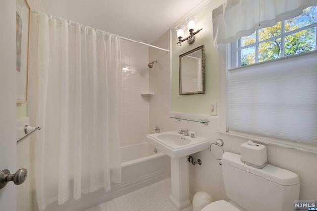 bathroom with tile patterned floors, shower / tub combo with curtain, tile walls, and toilet