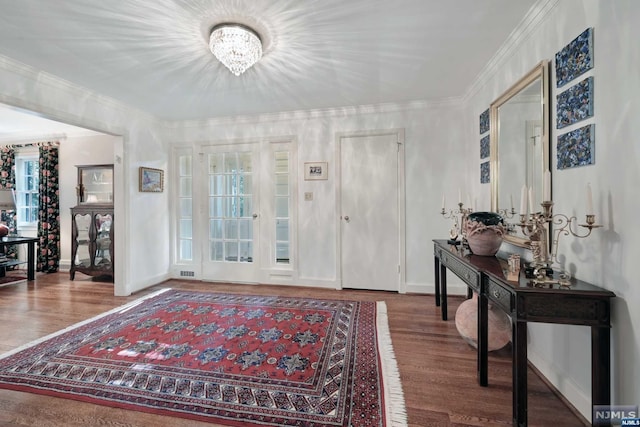 foyer entrance featuring hardwood / wood-style floors, a healthy amount of sunlight, ornamental molding, and a chandelier