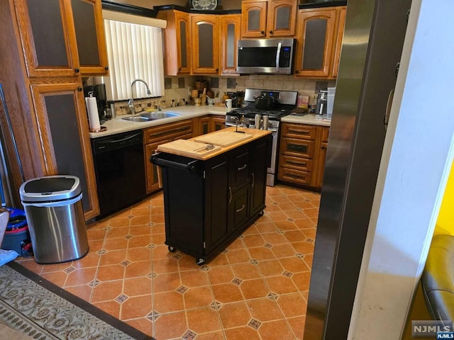 kitchen featuring appliances with stainless steel finishes, tasteful backsplash, a kitchen island, and sink