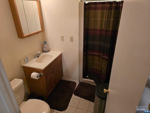 bathroom featuring tile patterned flooring, vanity, toilet, and walk in shower