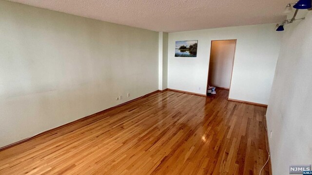 unfurnished room featuring a textured ceiling and hardwood / wood-style flooring