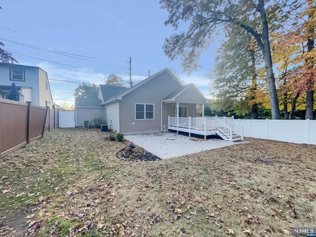 rear view of house with central air condition unit, a wooden deck, and a patio area