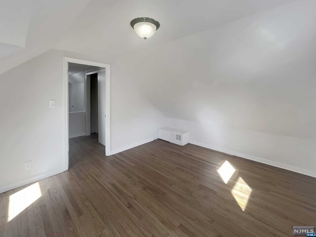 additional living space featuring dark hardwood / wood-style flooring and vaulted ceiling