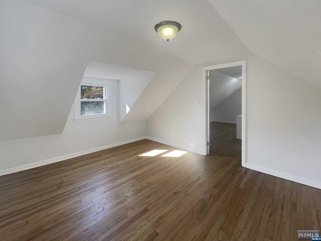 additional living space featuring dark hardwood / wood-style flooring and vaulted ceiling