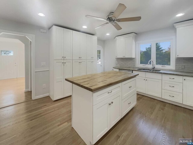 kitchen featuring white cabinetry, sink, dark hardwood / wood-style flooring, butcher block countertops, and decorative backsplash