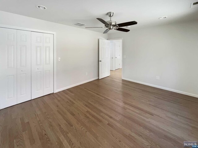 unfurnished bedroom featuring ceiling fan, a closet, and dark wood-type flooring